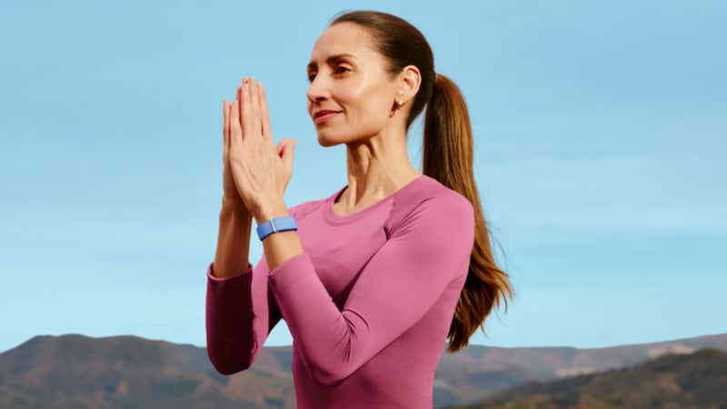 A person doing yoga while wearing a Google Fitbit Air.