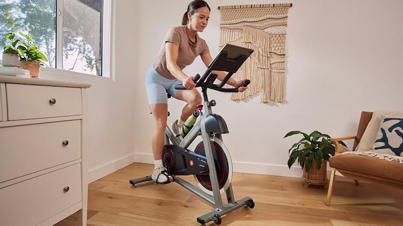 A person riding on an exercise bike, wearing shorts and a T-shirt.