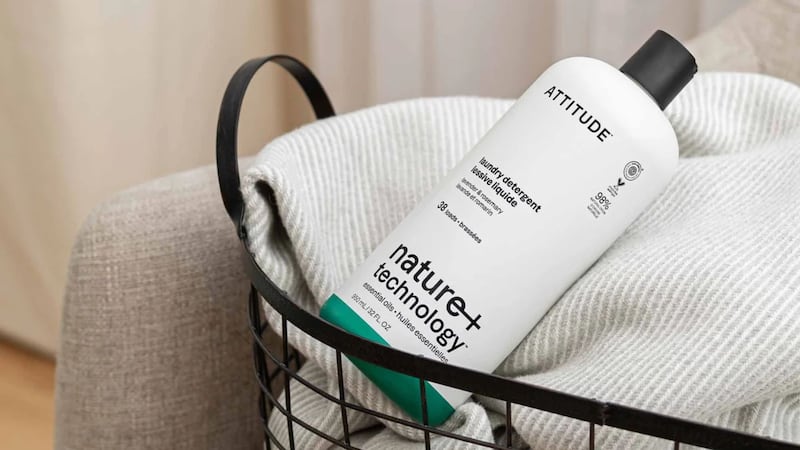 A bottle of ATTITUDE laundry detergent in a basket of laundry.